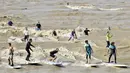 Sejumlah warga berselancar di Sungai Dordogne, Saint-Pardon, Prancis (24/7). Fenomena pasang surut besar yang menyebabkan gelombang arus di Sungai Dordogne ini dimanfaatkan warga dan turis unutk berselancar. (AFP Photo/Georges Gobet)