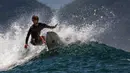 Seorang peselancar menaiki ombak di Pantai Lhoknga, Kabupaten Aceh Besar, Provinsi Aceh, Indonesia, 20 Februari 2023. Ombak Pantai Lhoknga yang besar dan garang telah terkenal di kalangan komunitas selancar lokal dan mancanegara. (CHAIDEER MAHYUDDIN/AFP)