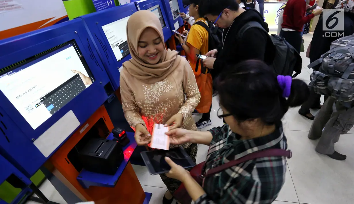 Petugas frontliner membantu calon penumpang membeli tiket di Stasiun Gambir, Jakarta, Minggu (21/4). PT KAI Daop 1 Jakarta mewajibkan petugas frontliner wanita dan pria mengenakan kebaya dan batik untuk menyambut Hari Kartini. (Liputan6.com/Johan Tallo)