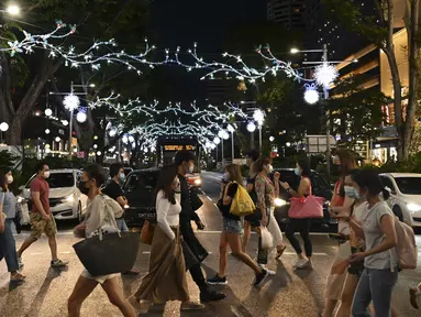 Orang-orang berjalan melewati dekorasi lampu Natal di luar pusat perbelanjaan di sepanjang kawasan Orchard road di Singapura, Selasa (8/12/2020). Mengusung tema Love This Christmas, acara tahun ini lebih sunyi karena aktivitas jalanan dibatasi di tengah pandemi Covid-19. (ROSLAN RAHMAN / AFP)