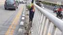 Seorang wanita menerobos pagar pembatas jalan di kawasan Pasar Minggu, Jakarta, Kamis (5/4). Kondisi Jembatan Penyeberangan Orang (JPO) yang tak kunjung diperbaiki membuat warga nekat menyeberang lewat celah pagar pembatas (Liputan6.com/Immanuel Antonius)