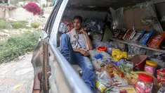 Majd al-Din al-Shamiri (16) menunggu pembeli di toko darurat di kawasan Jabal Sabr, Yaman pada 28 September 2019. Majd al-Din al-Shamiri mengubah mobil keluarganya yang rusak parah, akibat perang yang melanda, menjadi toko darurat untuk membantu keluarganya mencari nafkah. (Ahmad AL-BASHA/AFP)