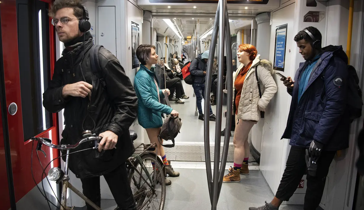 Dua wanita tanpa mengenakan celana berada di dalam kereta selama No Pants Subway Ride ke-18 di Amsterdam, Belanda (13/1). Acara ini dimulai pada tahun 2002 dengan peserta hanya tujuh orang. (AFP Photo/Olaf Kraak)