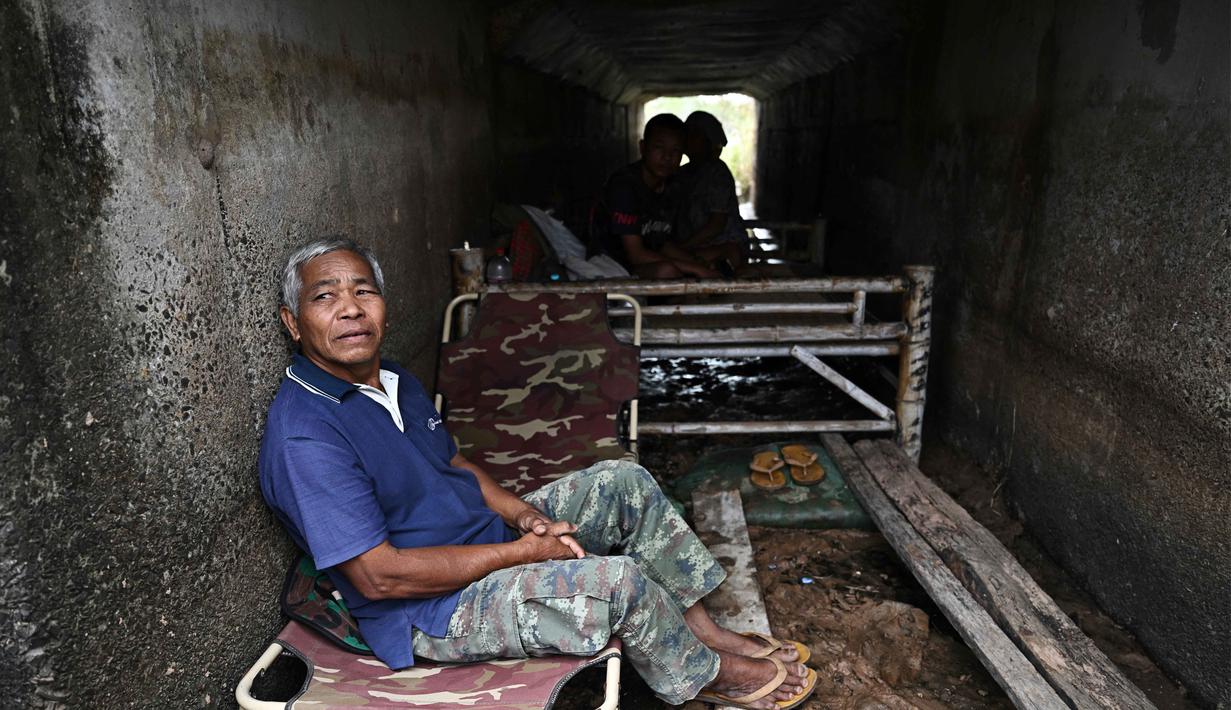 Mereka berlindung di beberapa lokasi yang dianggap aman, seperti pagoda, sekolah, dan tempat lainnya. Tampak dalam foto, petani Thailand, Boonkerd Yudeerum, duduk di dalam bunker bersama keluarganya di provinsi Surin pada Rabu 10 Desember 2025, selama bentrokan di sepanjang perbatasan Thailand-Kamboja. (Lillian SUWANRUMPHA/AFP)