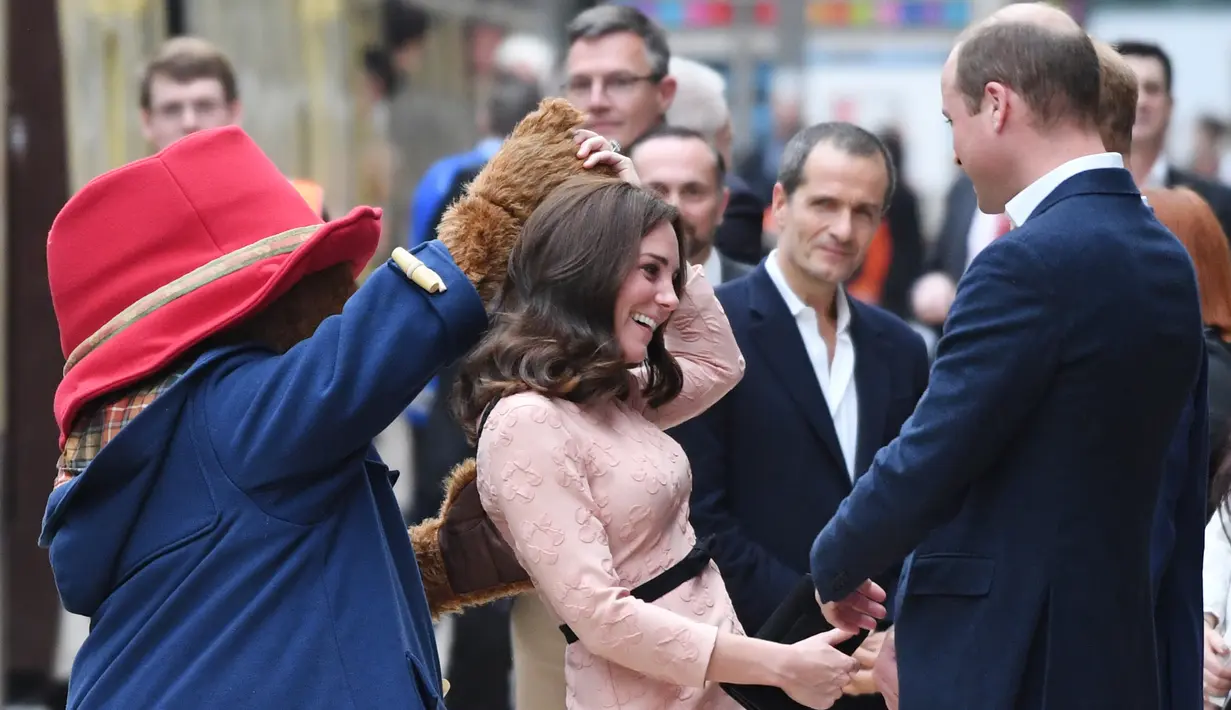 Pangeran William melihat Kate Middleton berdansa dengan seorang aktor berkostum Paddington di stasiun kereta Paddington, London, Senin (16/10). Kate dan William datang bersama Pangeran Harry, serta beberapa pemain film Paddington 2 (Chris J Ratcliffe/AFP)