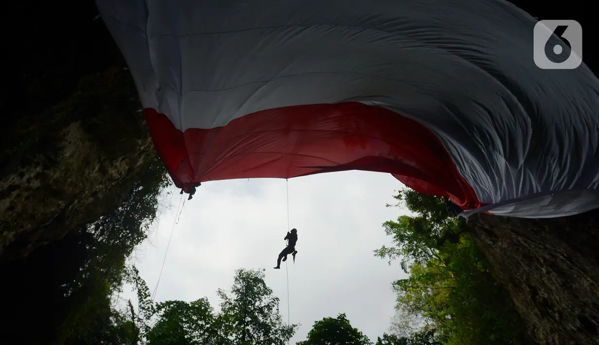 Jaringan Masyarakat Peduli Karst Klapanunggal membentangkan bendera merah putih dalam rangka peringatan HUT ke-75 RI di Tebing Kutalingkung, Klapa Nunggal, Jawa Barat, Senin (17/8/2020). Sebanyak 80 orang mengikuti pengibaran bendera berukuran 15 meter x 10 meter tersebut. (merdeka.com/Imam Buhori)