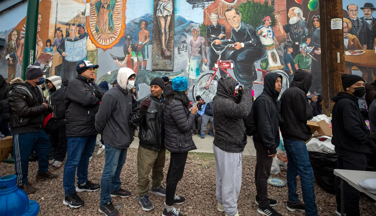 Para imigran mengantre untuk menerima makanan hangat yang disumbangkan warga di El Paso, Texas, Amerika Serikat, 18 Desember 2022. Kota-kota perbatasan Texas bersiap menghadapi lonjakan sebanyak 5.000 imigran baru setiap hari yang melintasi perbatasan AS-Meksiko karena pembatasan imigrasi era pandemi berakhir minggu ini. (AP Photo/Andres Leighton)