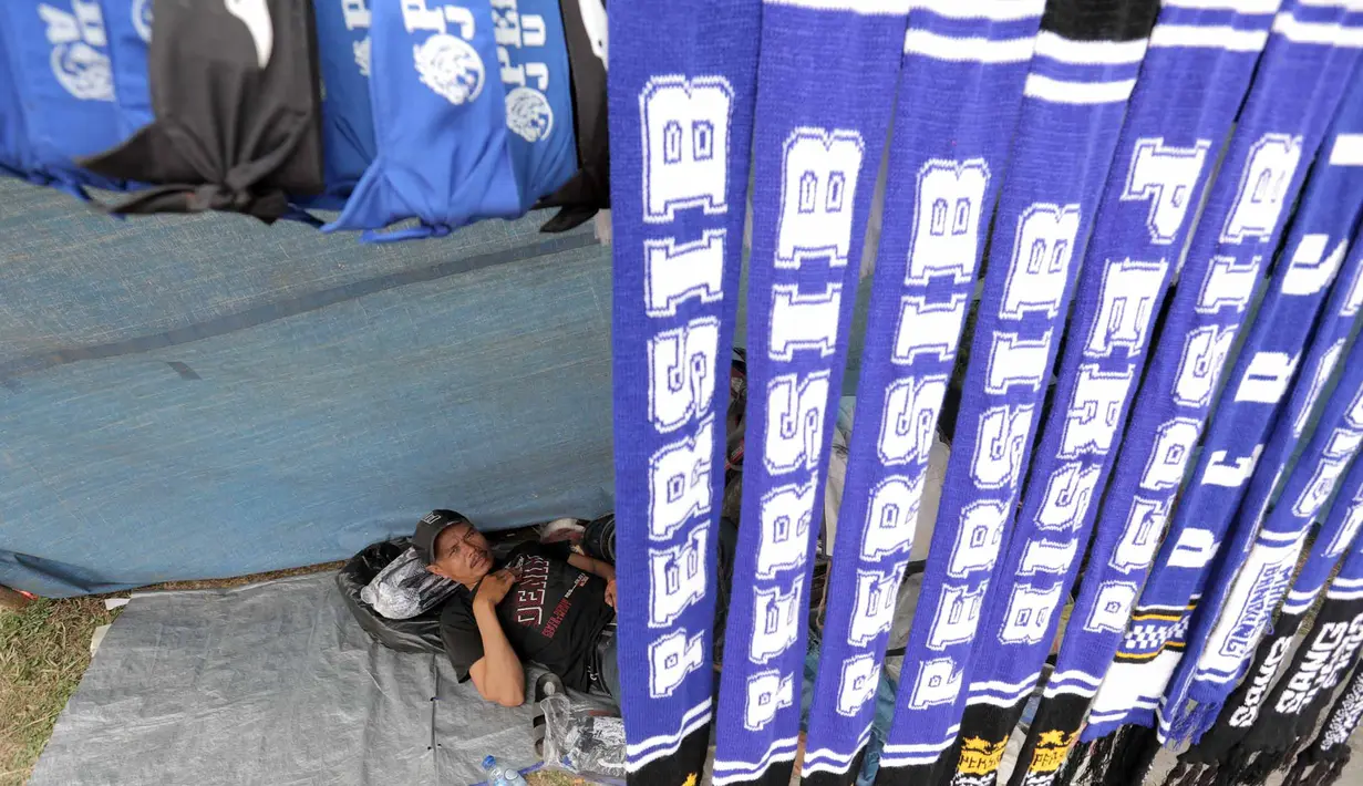 Seorang pedagang atribut santai menunggu pembeli dagangannya di Stadion Si Jalak Harupat, Bandung, Sabtu (24/10/2015). (Bola.com / Nicklas Hanoatubun)