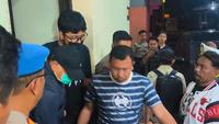 Bupati Sudewo berjaket biru, bertopi hitam dengan memakai masker dinaikan ke mobil dengan kawalan ketat aparat Polres Kudus