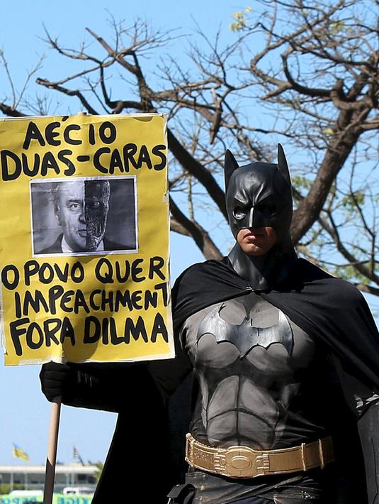 Aktivis mengenakan kostum Batman membawa tulisan berisi protes kepada Presiden Brasil Dilma Rousseff di Gedung Kongres Nasional, Brasil (27/5/2015). Tuntutan ini didasari banyaknya kasus korupsi yang menjerat Presiden Dilma. (REUTERS/Adriano Machado)