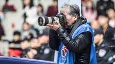 Fotografer Hong Nanli mengambil gambar saat pertandingan bola basket di Shanghai (16/1). Hong Nanli 79 tahun memulai karirnya sebagai fotografer sejak 1979, ia juga merupakan fotografer olah raga tertua di China. (AFP Photo/China Out)