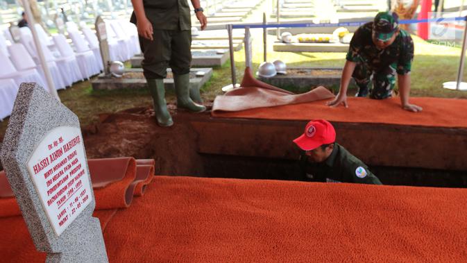 Pekerja menggali makam Presiden ke-3 RI BJ Habibie di TMP Kalibata, Jakarta, Kamis (12/9/2019). Makam Habibie bersebelahan dengan sang istri tercinta, Ainun Habibie. (Liputan6.com/Herman Zakharia)