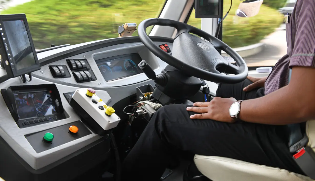 Seorang pengemudi duduk dalam bus tanpa sopir selama uji coba publik di kawasan wisata Pulau Sentosa, Singapura pada 20 Agustus 2019. Untuk menjaga hal-hal yang tidak diinginkan, bus otonom ini menyediakan sopir untuk mengambil kendali jika diperlukan. (Roslan RAHMAN/AFP)