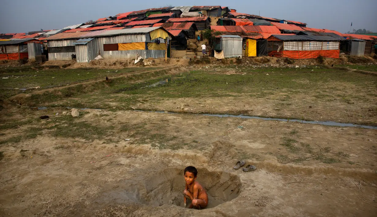 Seorang anak bermain tanah dengan latar belakang tenda-tenda pengungsian di kamp pengungsi Jamtoly, Bangladesh (15/1). (AP Photo / Manish Swarup)