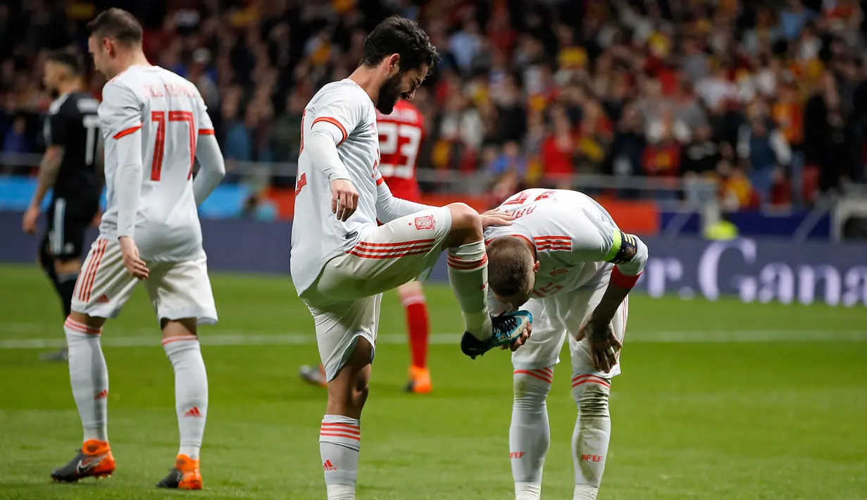 Kapten timnas Spanyol, Sergio Ramos mencium sepatu rekan setimnya Isco Alarcon usai mencetak gol kedua saat pertandingan persahabatan melawan Argentina di stadion Wanda Metropolitano di Madrid (27/3). (AP Photo / Paul White)