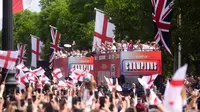 Para penggemar melambaikan tangan ke arah bus yang membawa para pemain dan staf selama perayaan kemenangan kepulangan timnas putri Inggris di The Mall di luar Istana Buckingham di London pada 29 Juli 2025 setelah tim tersebut memenangkan Euro 2025. (Adam Davy/POOL/AFP)