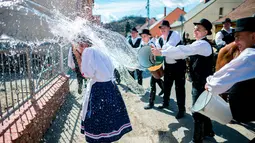 Para pria berkostum rakyat Szekler Bukovina menyiram air ke seorang wanita muda di Ciko, selatan Budapest, Senin (3/4). Tradisi Paskah populer di Hungaria ini dilakukan pada Senin Paskah yang juga dikenal dengan nama Ducking Monday (Tamas Soki/MTI via AP)