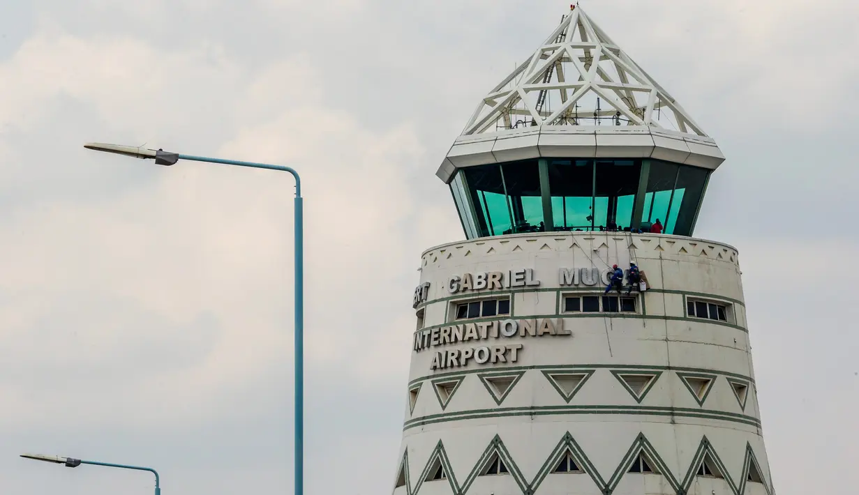 Pekerja menyelesaikan memasang plang nama Bandara Robert Mugabe yang baru berganti nama, di Harare, Kamis (9/11). Pemerintah Zimbabwe mengganti nama bandara mereka yang semula bernama Bandara Harare menjadi Bandara Robert Mugabe.  (Jekesai NJIKIZANA/AFP)