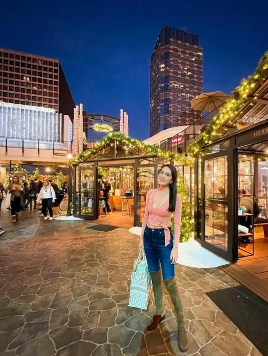 Padu padan crop top warna peach dengan celana jeans, dan high knee boots bikin look makin terlihat fashionable. (Instagram/shandyaulia).