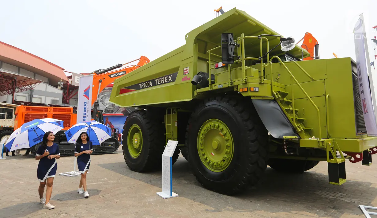 Model berjalan dekat alat berat pada pameran industri Mining Indonesia di JIExpo Kemayoran, Jakarta, Rabu (18/9/2019). Pameran bertajuk Indonesia Energy and Engineering Series Exhibition diikuti 1.400 perusahaan dari 39 negara. (Liputan6.com/Fery Pradolo)