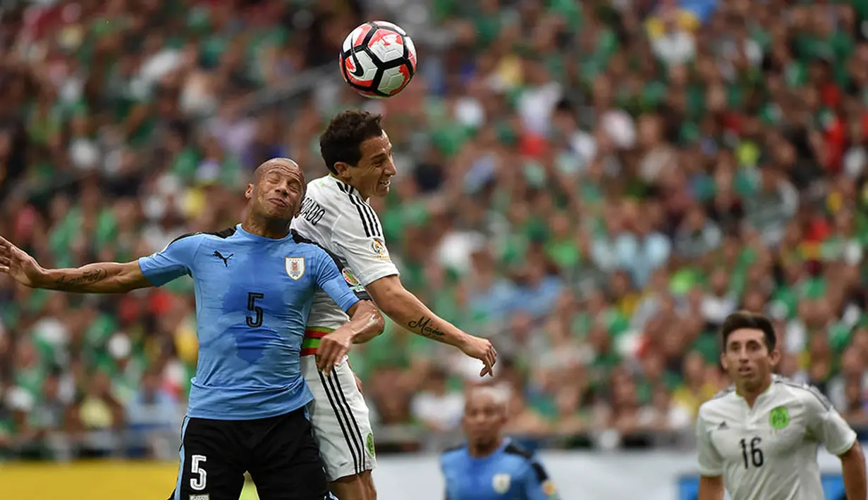 Pemain Uruguay, Carlos Sanchez, duel udara dengan pemain Meksiko, Andres Guardado, pada laga Grup C Copa Amerika. Keunggulan Meksiko tercipta melalui bunuh diri Alvaro Pereira serta gol dari Rafale Marquez dan Hector Herrera. (AFP/Nelson Almeida)