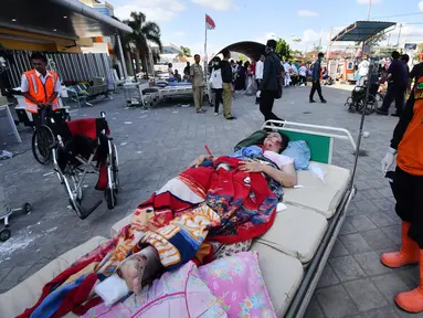 Korban gempa Lombok yang terluka menunggu bantuan medis di luar Rumah sakit Moh. Ruslan di Mataram, Senin (6/8). Aparat gabungan terus melakukan evakuasi dan penanganan darurat akibat bencana gempa bermagnitudo 7 yang mengguncang Lombok. (AFP/ADEK BERRY)
