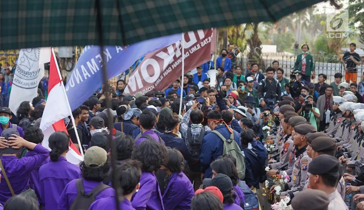 Sejumlah personel polisi memegang bunga saat mengamankan aksi unjuk rasa Badan Eksekutif Mahasiswa Seluruh Indonesia (BEM SI) di sekitar Gedung DPR RI, Jakarta, Selasa (1/10/2019). (Liputan6.com/Immanuel Antonius)