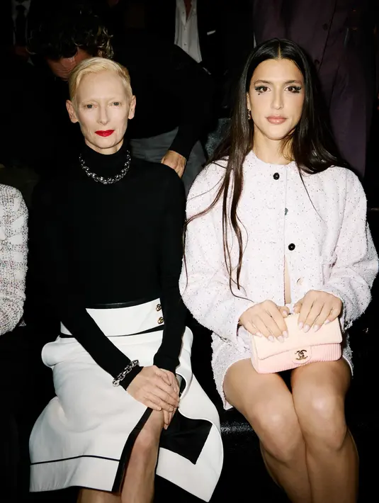 Aktris senior Tilda Swinton kenakan turtleneck hitam dan rok midi slit hitam putih. Kalung dan gelang rantai jadi aksen yang statement [Chanel]