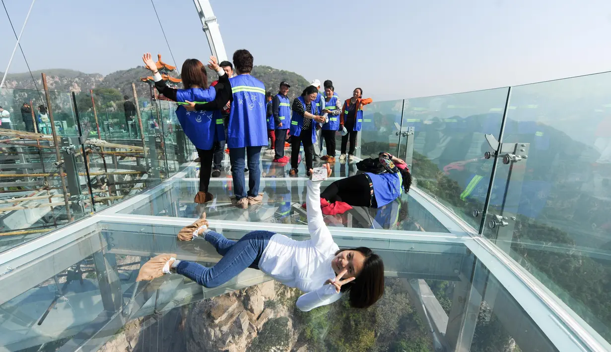 Pengunjung berselfie di atas panggung berlantai kaca yang berada di pinggir tebing di Shilinxia, Beijing, 30 april 2016. Panggung kaca yang menggantung hingga 32.8 meter dari tepi tebing ini merupakan objek wisata baru di China. (AFP PHOTO/STR)