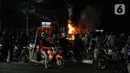 Warga menyaksikan sebuah mobil terbakar di Jalan Asia Afrika, Jakarta, Kamis (18/3/2021) dinihari. Api yang awalnya kecil akhirnya membesar hingga menghanguskan seluruh bagian mobil. (Liputan6.com/Johan Tallo)