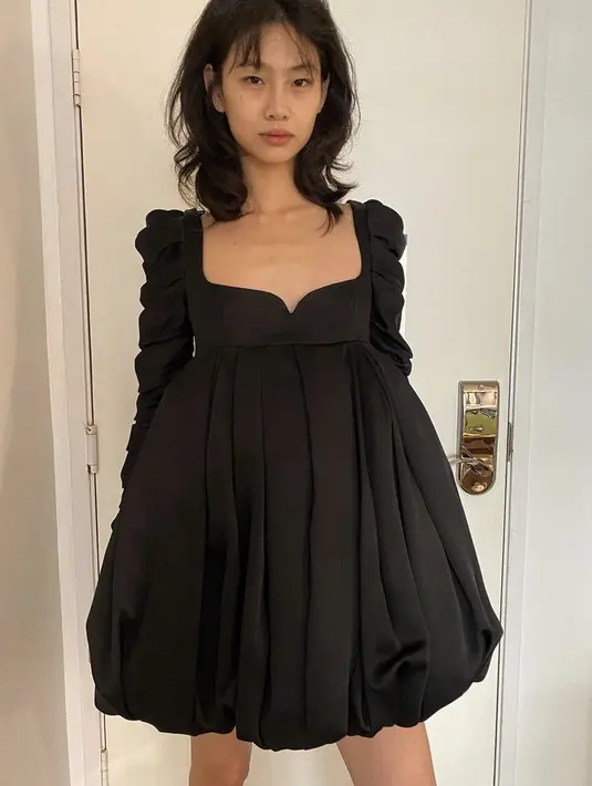 Atau mengenakan mini dress dari brand Khaite dengan model heart neck yang memerlihatkan tulang pundak dan dadanya.