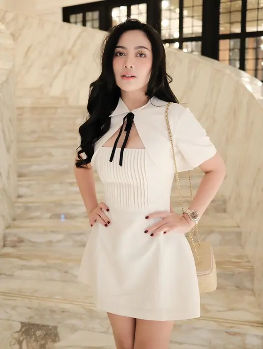 Penampilan manis penuh pesona Rachel Vennya pakai mini dress putih dengan detail cape berkerah dan pita kecil yang manis berwarna hitam. [Foto: Instagram/rachelvennya]
