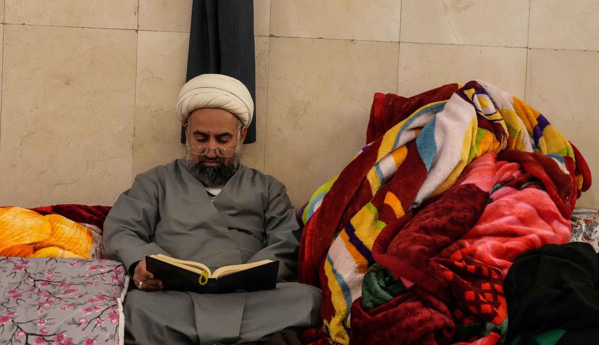 Seorang Muslim Syiah membaca Al-Quran saat melaksanakan Itikaf di Masjid Kufa, selatan Baghdad, Irak, pada 12 Maret 2026. (Qassem al-KAABI/AFP)