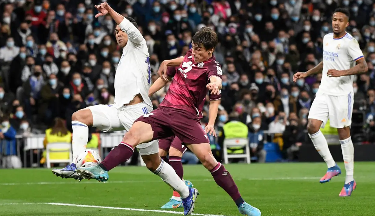 Pemain Real Madrid Casemiro (kiri) berebut bola dengan pemain Real Sociedad Robin Le Normand pada pertandingan sepak bola Liga Spanyol di Stadion Santiago Bernabeu, Madrid, Spanyol, 5 Maret 2022. Real Madrid menang 4-1. (PIERRE-PHILIPPE MARCOU/AFP)