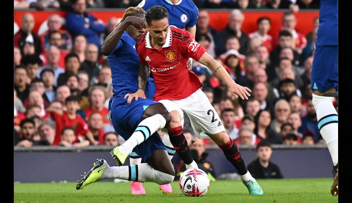 Pemain Chelsea, Trevoh Chalobah (kiri), berusaha menghentikan laju pemain Manchester United, Antony, dalam pertandingan partai tunda pekan ke-32 Liga Inggris 2022/2023 yang berlangsung di Old Trafford, Jumat (26/5/2023) dini hari WIB. (AFP/Oli Scarff)