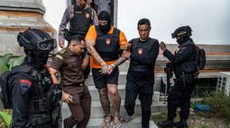 Tiga orang tersangka warga negara Australia yakni Tupou Pasa Midolmore, Coskun Mevlut, dan Darcy Francesco Jenson menjalani proses pelimpahan tahap II (tersangka dan barang bukti) dari penyidik Polres ke pihak Kejaksaan Negeri (Kejari) Badung, Bali pada 15 Oktober 2025. Tampak dalam foto, tersangka Tupou Pasa Midolmore (tengah) saat dibawa kembali ke rumah tahanan setelah menjalani pemeriksaan oleh pihak kejaksaan di Badung, Bali, pada 15 Oktober 2025. (Dicky Bisinglasi/AFP)