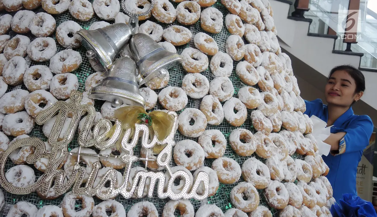 Karyawan menghiasi pohon Natal yang terbuat dari susunan donat di lobby hotel Dafam Semarang, Rabu (12/12). Pohon Natal setinggi 3 meter untuk menyambut Natal tersebut terdapat 2000 buah kue donat. (Liputan6.com/Gholib)