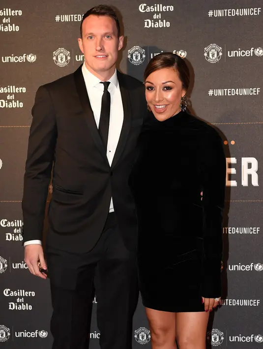 Bek Manchester United, Phil Jones menggandeng istrinya Kaya Hall di karpet merah makan malam acara amal UNICEF di Old Trafford, Rabu (15/11). Event ini sekaligus ajang pamer istri dan kekasih (WAGs) pasukan Red Devils. (Paul ELLIS/AFP)