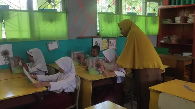 Hasmawati melihat anak didiknya membaca buku cerita yang dibuatnya sendiri.