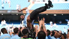 Manajer Manchester City Pep Guardiola dilemparkan ke udara oleh para pemainnya usai melawan Huddesfiel dalam pertandingan Liga Inggris di Etihad Stadium (6/5). (AFP/Oli Scraff)