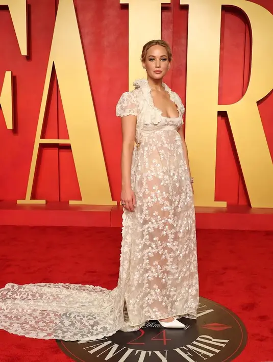 Jennifer Lawrence mengenakan pakaian Givenchy Haute Couture Musim Gugur Musim Dingin 1996.  Gaun waist dress dengan organza sutra putih dihiasi dengan sulaman clover warna senada, dikenakan dengan mantel berlengan balon pendek dan bahan organza sutra putih dihiasi dengan ornamen acanthus tone-on-tone. [Givenchy]