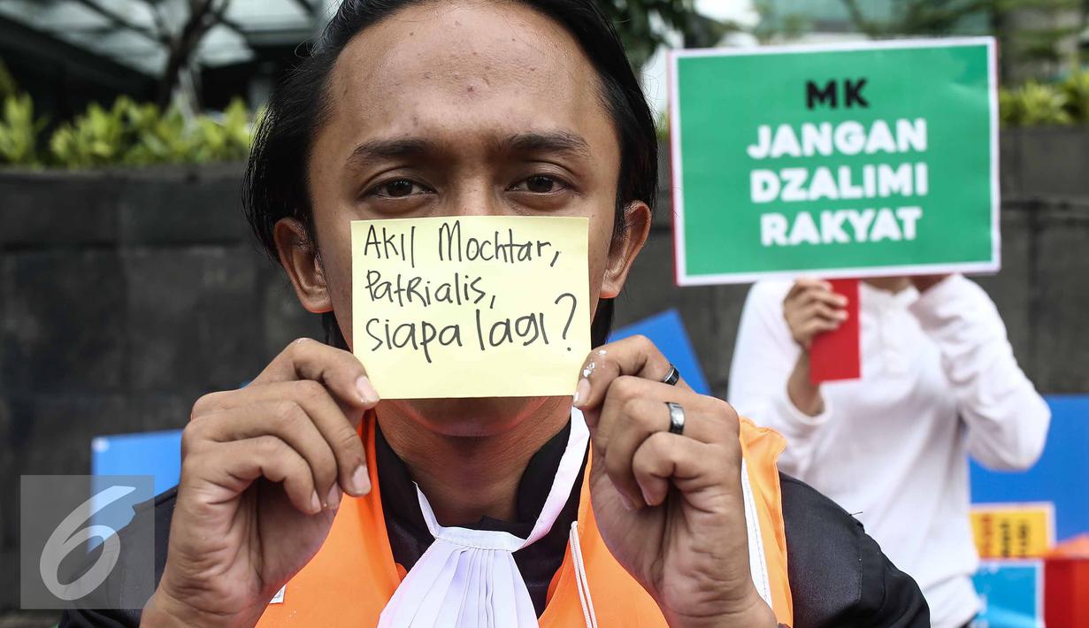 Seorang peserta aksi menunjukan tulisan nama tokoh yang terlibat kasus suap saat Car Free Day dikawasan Bunderan HI, Jakarta, Minggu (12/2). Aksi tersebut untuk menanggapi kasus Hakim Mahkamah Konstitusi, Patrialis Akbar. (Liputan6.com/Faizal Fanani)