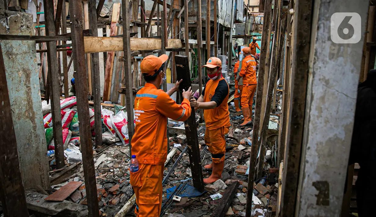 Para pekerja menyelesaikan pembangunan rumah panggung di dekat bantaran Kali Ciliwung, Kampung Melayu, Jakarta, Rabu (7/4/2021). Pemerintah Provinsi DKI Jakarta melakukan renovasi terhadap 40 hunian warga Kampung Melayu menjadi rumah panggung. (Liputan6.com/Faizal Fanani)