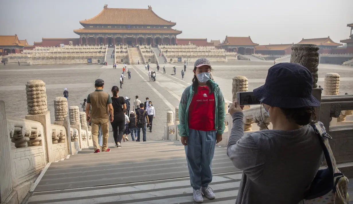 Pengunjung mengenakan masker saat berpose di Kota Terlarang, Beijing, China, Jumat (1/5/2020). Kota Terlarang kembali dibuka setelah ditutup lebih dari tiga bulan karena pandemi virus corona COVID-19. (AP Photo/Mark Schiefelbein)