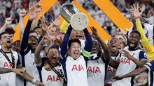 Son Heung-min (tengah) mengangkat trofi bersama para pemain Tottenham setelah menjuarai final Liga Europa 2024/2025 di Stadion San Mames, Bilbao, Spanyol, Kamis (22/05/2025) WIB. Tottenham menang dengan skor 1-0 atas Manchester United. (AFP/Thomas Coex)
