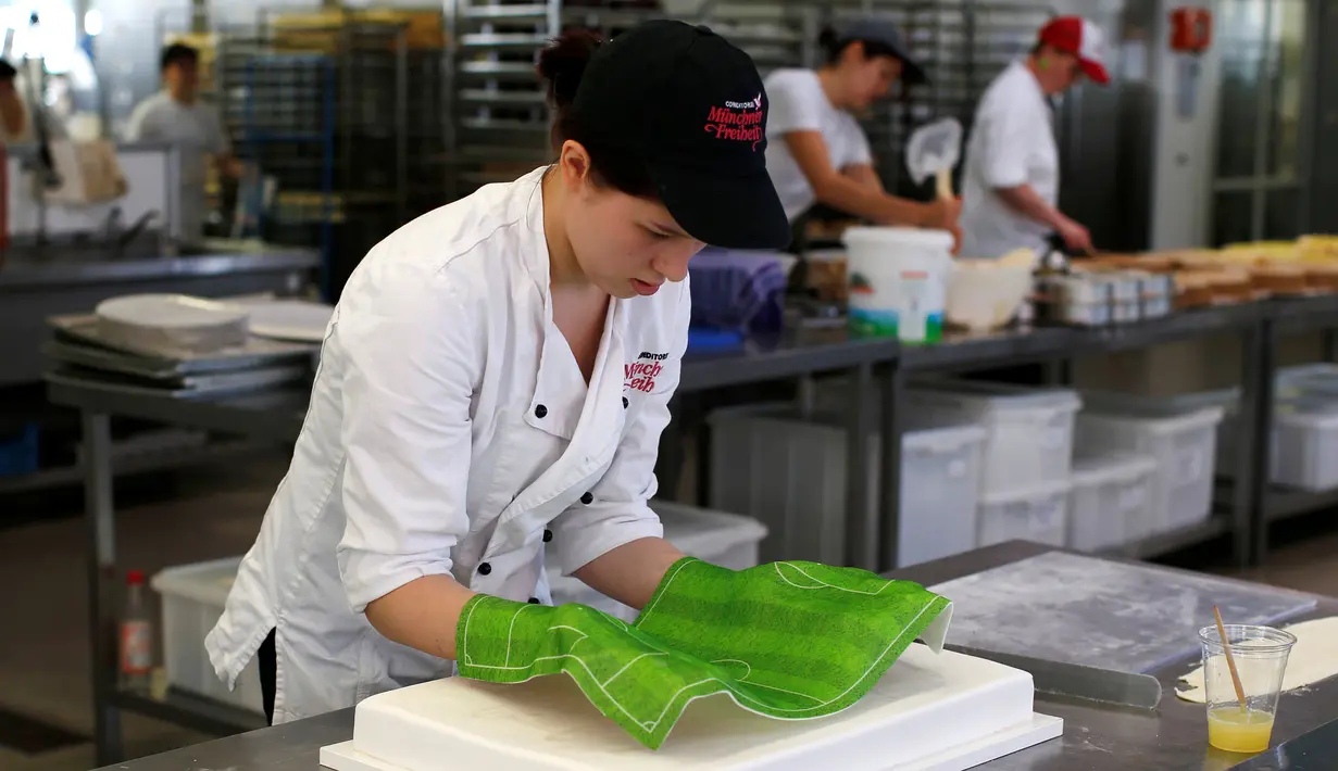 Pembuat kue meletakkan hiasan di atas kue Euro 2016 yang dibuat di sebuah tempat pembuatan kue di Munich, Jerman, Senin (20/6). Beraneka kue bertema Euro 2016 mewarnai perhelatan sepakbola Eropa. (REUTERS/Michaela Rehle)
