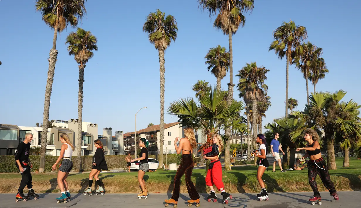 Orang-orang bermain sepatu roda di sepanjang Venice Beach di Venice, California, Kamis (3/9/2020). Permintaan sepatu roda di Amerika Serikat mengalami peningkatan tajam untuk mencari aktivitas di luar ruangan di tengah pembatasan sosial akibat corona Covid-19. (Mario Tama/Getty Images/AFP)