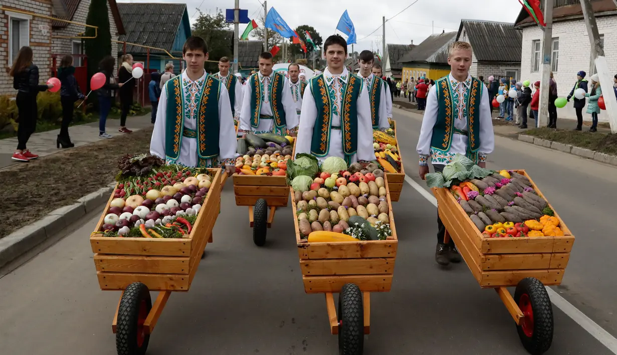 Sejumlah pria mengenakan pakaian adat Belarusia mendorong gerobak berisikan sayuran dalam Festival Dozynki di Minsk, Belarusia, Minggu (7/10). Warga Belarusian rayakan pengumpulan hasil panen dalam festival ini. (AP Photo/Sergei Grits)