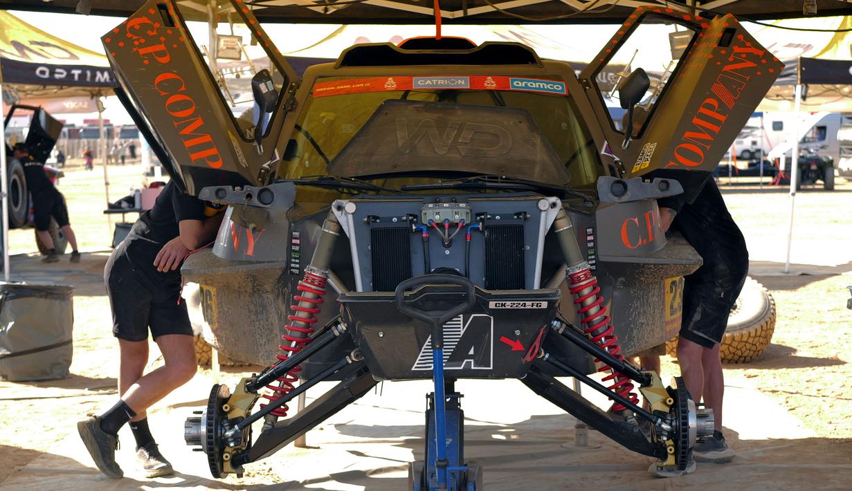 Sejumlah mekanik tengah memeriksa mobil menjelang ajang Reli Dakar 2025 pada Rabu (01/01/2025) waktu setempat di Bisha, Arab Saudi. Ajang tersebut akan berlangsung pada 3 hingga 17 Januari 2025. (AFP/Valery Hache)