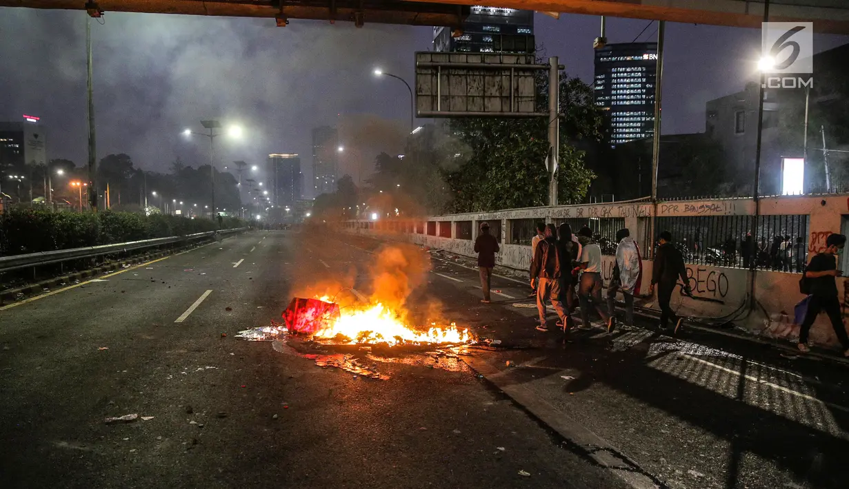 Api membakar penghalang jalan di Jalan Gatot Soebroto pasca demonstrasi mahasiswa di depan Gedung DPR/MPR, Jakarta, Selasa (24/9/2019). Demonstrasi mahasiswa di depan gedung DPR RI berujung ricuh, polisi menembakkan gas air mata dan water cannon untuk membubarkan demo. (Liputan6.com/Faisal Fanani)